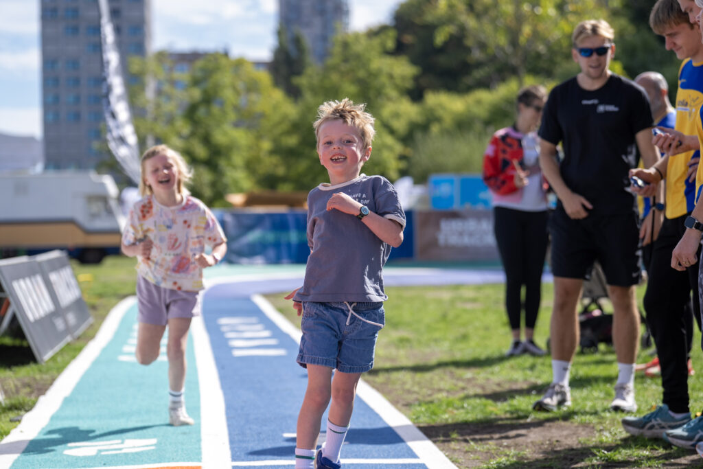 rennend kind met een glimlach op een atletiekbaan in een park